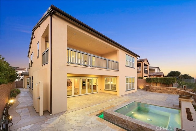 2598 E Temblor Ranch Dr, Brea, CA 92821 - back of house at dusk featuring a balcony, stucco siding, an in-ground hot tub, and a fenced backyard