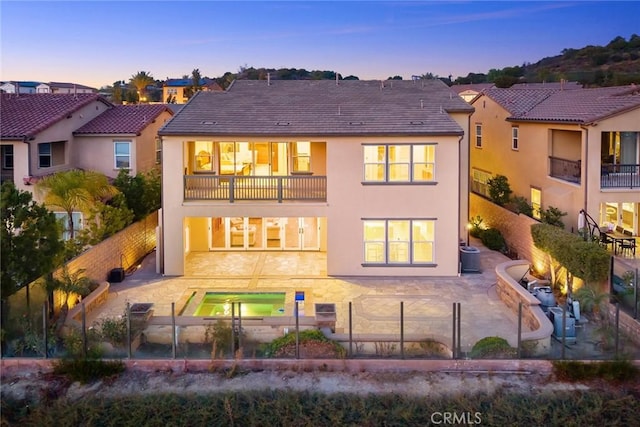 2598 E Temblor Ranch Dr, Brea, CA 92821 - back of house at dusk with a balcony, a fenced backyard, stucco siding, and a patio area