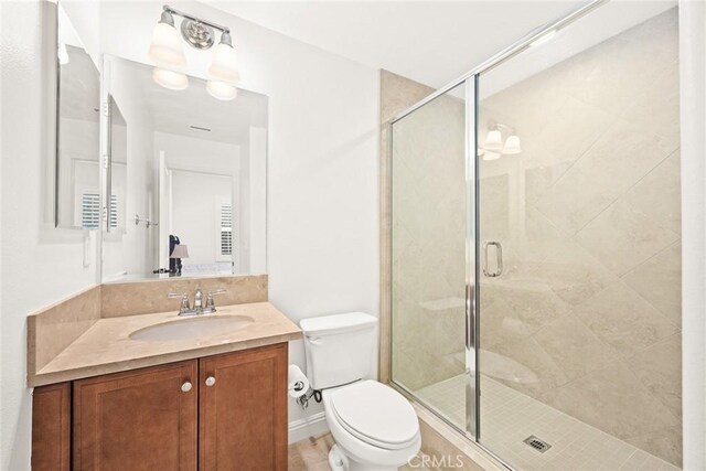 bathroom featuring vanity, a shower with shower door, and toilet