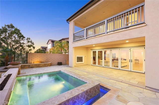 pool at dusk with a jacuzzi and a patio area