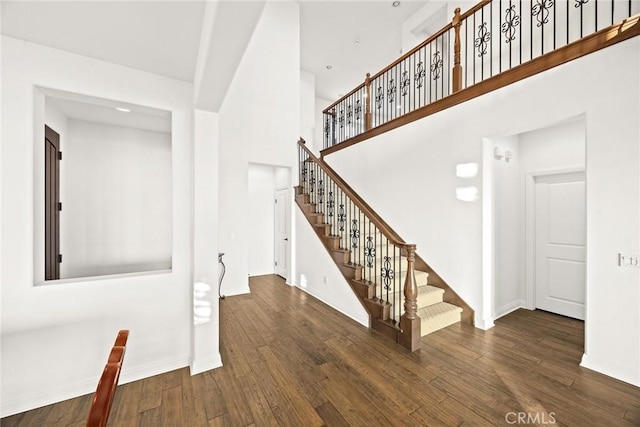 stairway with hardwood / wood-style floors and a high ceiling