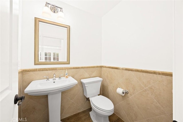 bathroom featuring sink, tile walls, and toilet