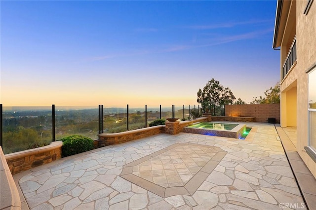 pool at dusk with an in ground hot tub and a patio