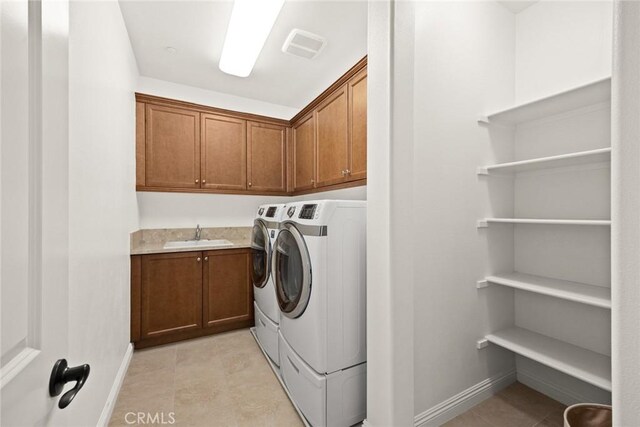 washroom with light tile patterned flooring, cabinets, washer and clothes dryer, and sink