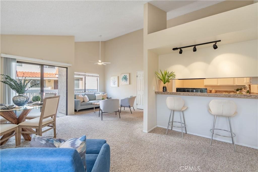 carpeted living room featuring track lighting, high vaulted ceiling, and ceiling fan