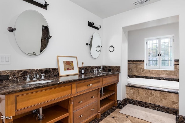 bathroom with vanity and tiled tub