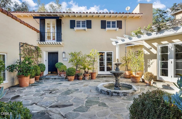 back of house featuring french doors, a balcony, and a patio