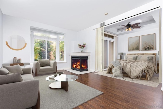 bedroom with a tray ceiling, wood-type flooring, and ceiling fan