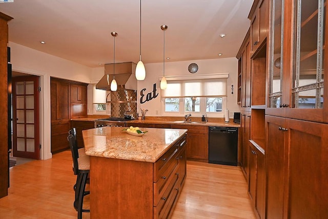 kitchen with a breakfast bar area, dishwasher, light stone countertops, a kitchen island, and exhaust hood