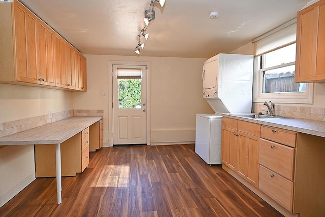 clothes washing area with stacked washer and clothes dryer, sink, cabinets, track lighting, and dark hardwood / wood-style flooring