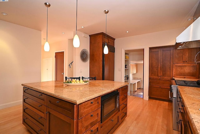 kitchen with built in appliances, a center island, light hardwood / wood-style floors, and hanging light fixtures