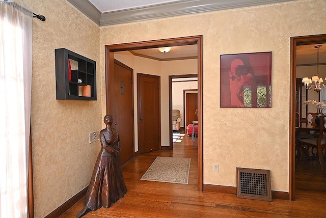 hallway with hardwood / wood-style floors, a notable chandelier, and ornamental molding