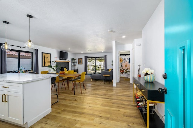 kitchen featuring light stone counters, light hardwood / wood-style flooring, hanging light fixtures, and white cabinets