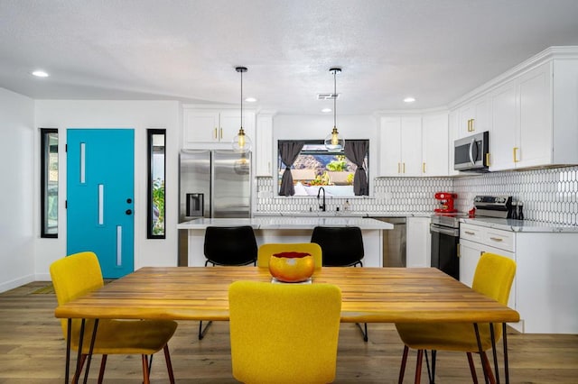 kitchen featuring pendant lighting, white cabinetry, stainless steel appliances, and a kitchen island