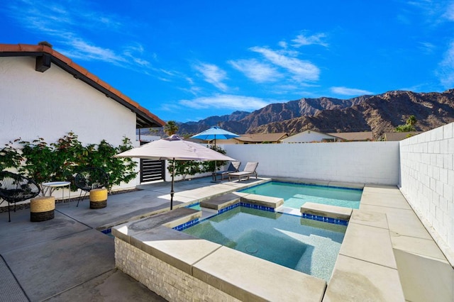 view of pool featuring a mountain view, a patio, and an in ground hot tub