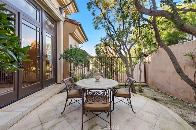 view of patio featuring french doors, outdoor dining area, and fence