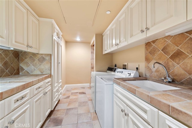 clothes washing area with cabinet space, washing machine and clothes dryer, recessed lighting, and a sink