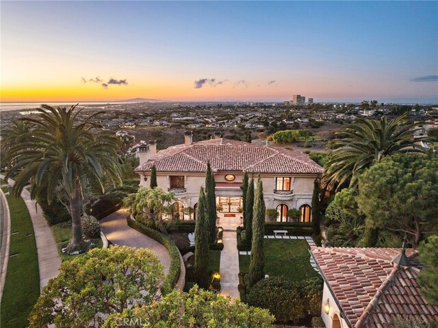 mediterranean / spanish home with a chimney, a tile roof, and stucco siding