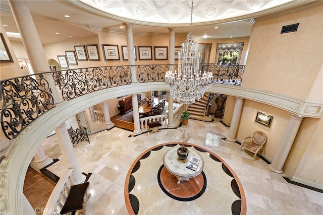 stairs with decorative columns, ornamental molding, a towering ceiling, and an inviting chandelier