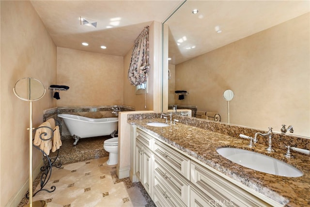 bathroom featuring a soaking tub, a sink, double vanity, and toilet