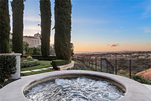 pool at dusk featuring an in ground hot tub