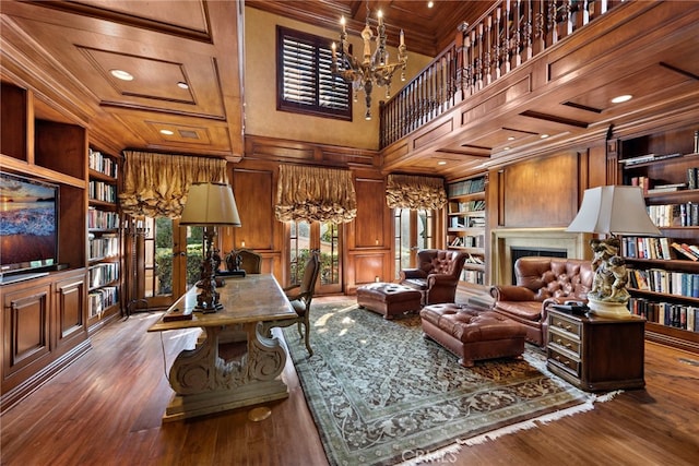 interior space featuring built in features, an inviting chandelier, ornamental molding, dark hardwood / wood-style flooring, and wood walls