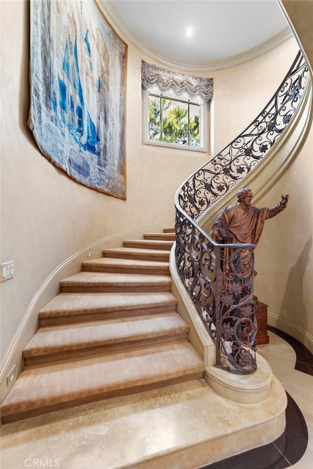 staircase with a towering ceiling and ornamental molding