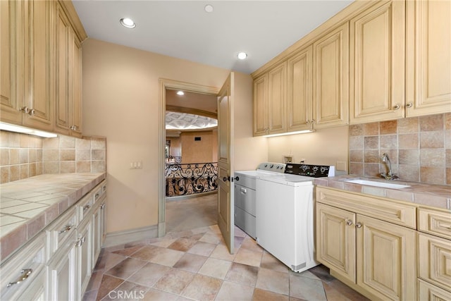 washroom featuring a sink, baseboards, recessed lighting, cabinet space, and washer and dryer