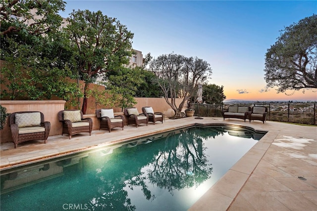 pool at dusk with a patio area