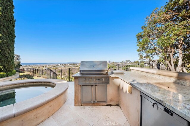 view of patio with fence, area for grilling, exterior kitchen, and an in ground hot tub