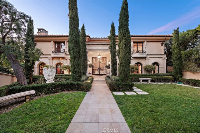 mediterranean / spanish-style house featuring a balcony and a front yard