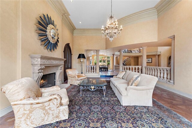 living area with a chandelier, baseboards, ornate columns, and ornamental molding