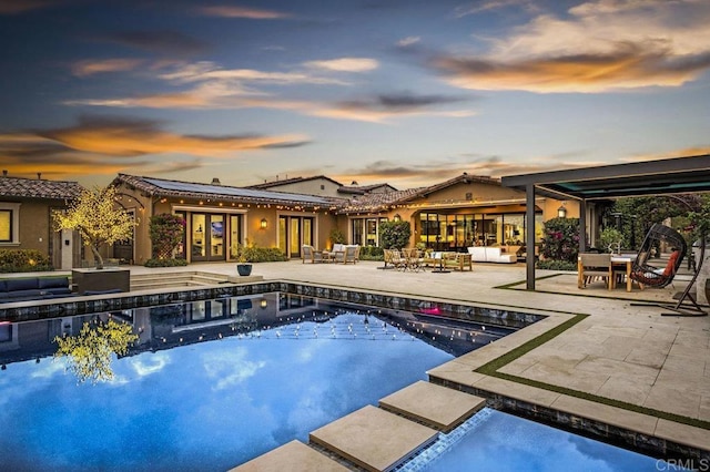 pool at dusk with area for grilling and a patio area