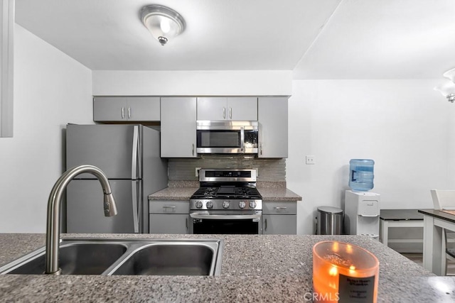 kitchen featuring tasteful backsplash, appliances with stainless steel finishes, sink, and gray cabinetry