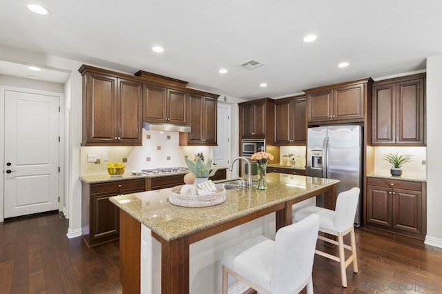 kitchen featuring dark hardwood / wood-style floors, an island with sink, sink, a breakfast bar area, and stainless steel appliances