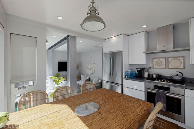 kitchen featuring wall chimney exhaust hood, white cabinetry, and appliances with stainless steel finishes