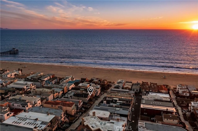 aerial view at dusk with a water view and a beach view