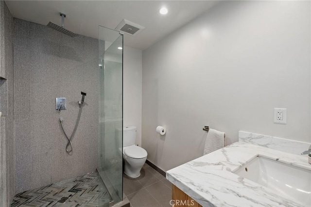 bathroom featuring vanity, tile patterned flooring, toilet, and a tile shower