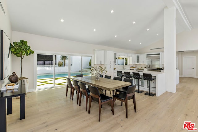 dining area featuring high vaulted ceiling and light hardwood / wood-style floors