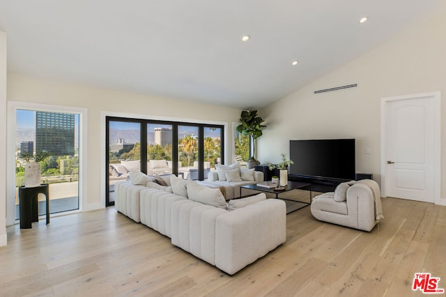 living room featuring lofted ceiling, a healthy amount of sunlight, and light hardwood / wood-style flooring