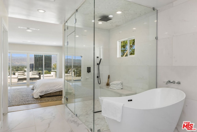 bathroom with plenty of natural light, separate shower and tub, and tile walls