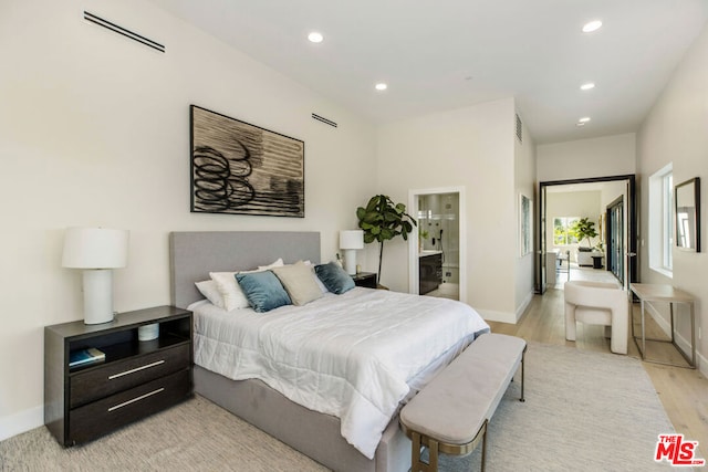 bedroom featuring connected bathroom and light hardwood / wood-style floors