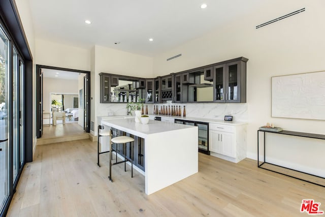 kitchen featuring a kitchen island, a kitchen bar, white cabinets, and light hardwood / wood-style floors