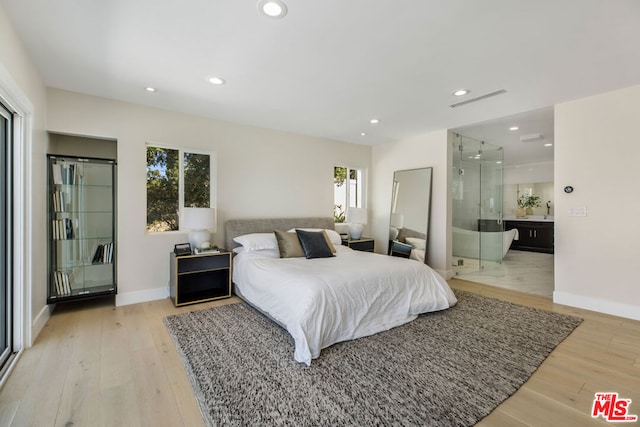 bedroom with ensuite bath and light hardwood / wood-style flooring