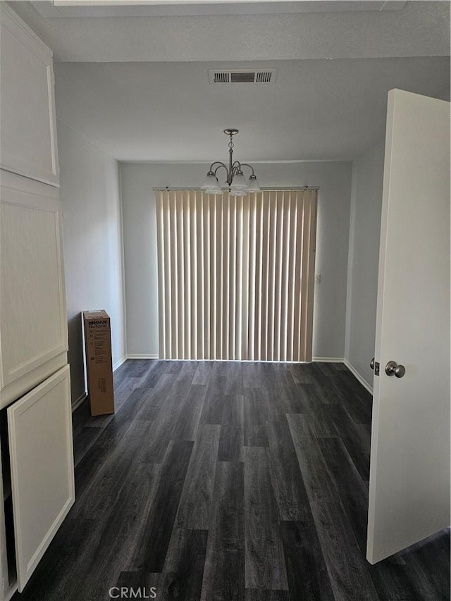 unfurnished dining area with a notable chandelier and dark hardwood / wood-style floors