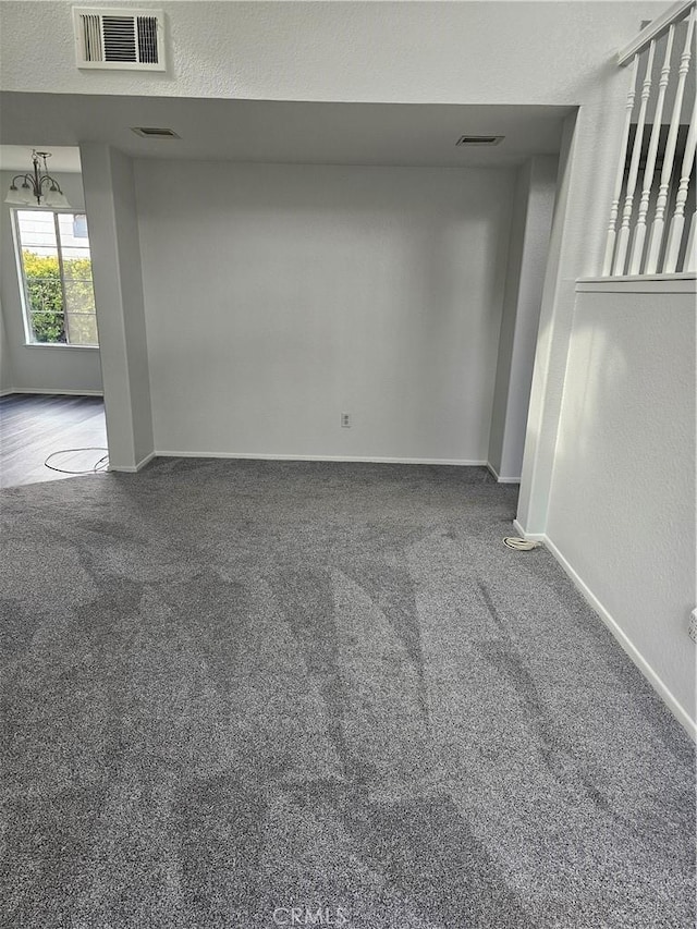 carpeted empty room with a notable chandelier