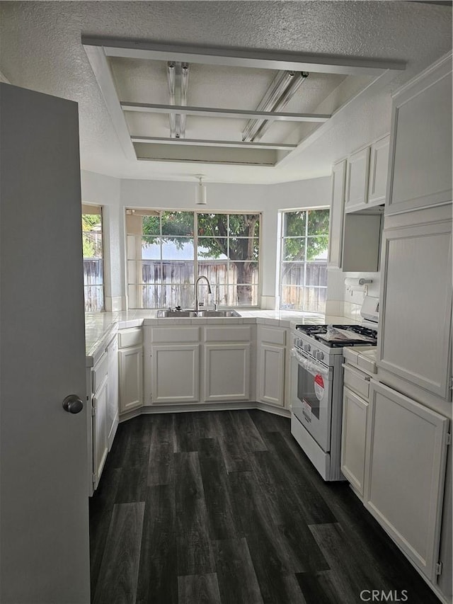 kitchen with white range with gas cooktop, sink, white cabinetry, and plenty of natural light