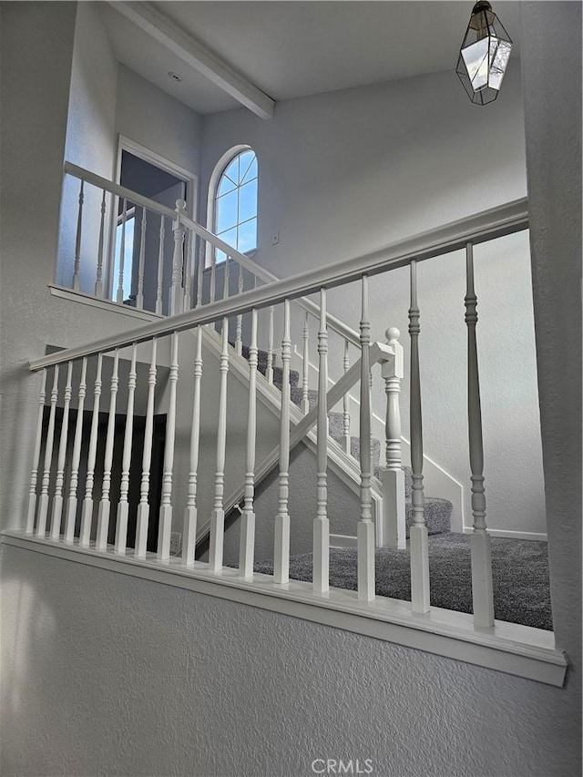 staircase featuring beamed ceiling