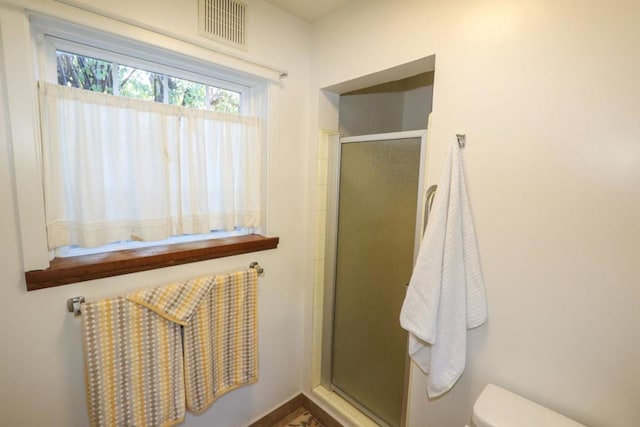 bathroom featuring toilet and a shower with shower door