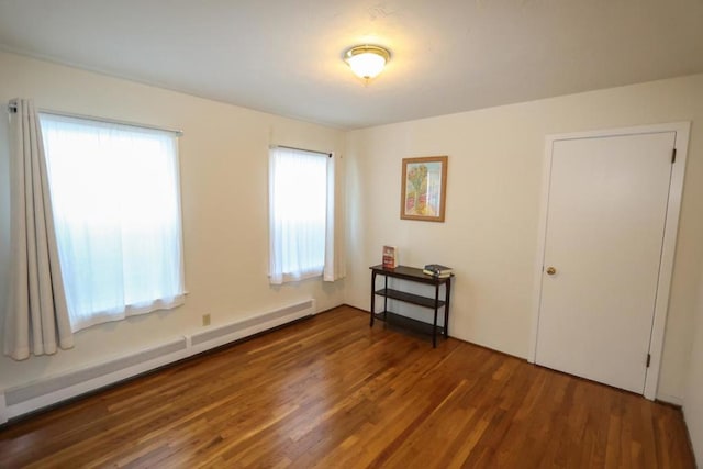 unfurnished room with a baseboard radiator and dark wood-type flooring